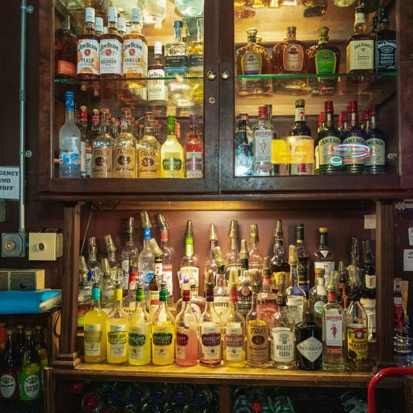 A well-stocked bar at Woody's @ City Market, featuring various liquor bottles on shelves.