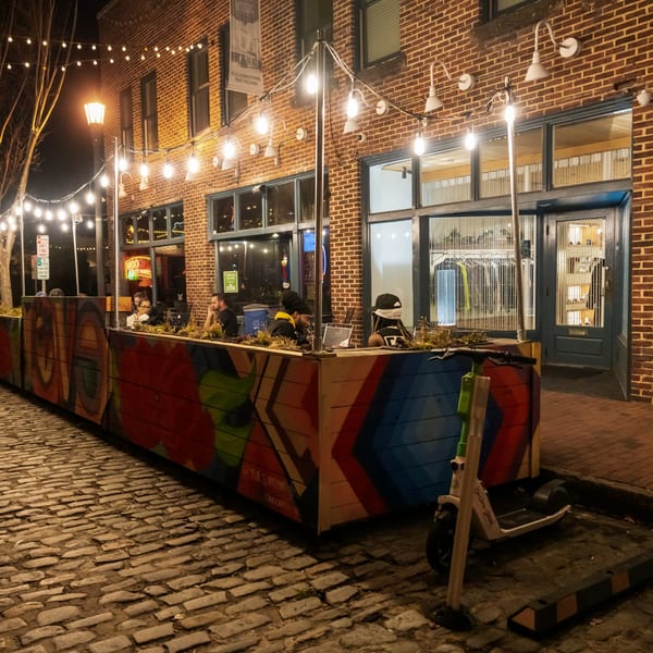 Night view of Woody's @ City Market's outdoor patio with string lights and patrons.