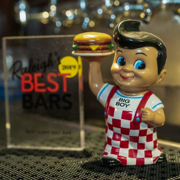 A Big Boy statue holding a burger next to a "Raleigh's Best Bars 2019" award.